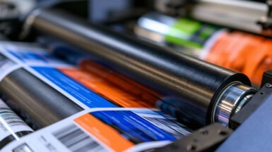Industrial printing press rolling out vibrant labels with barcodes in a factory
